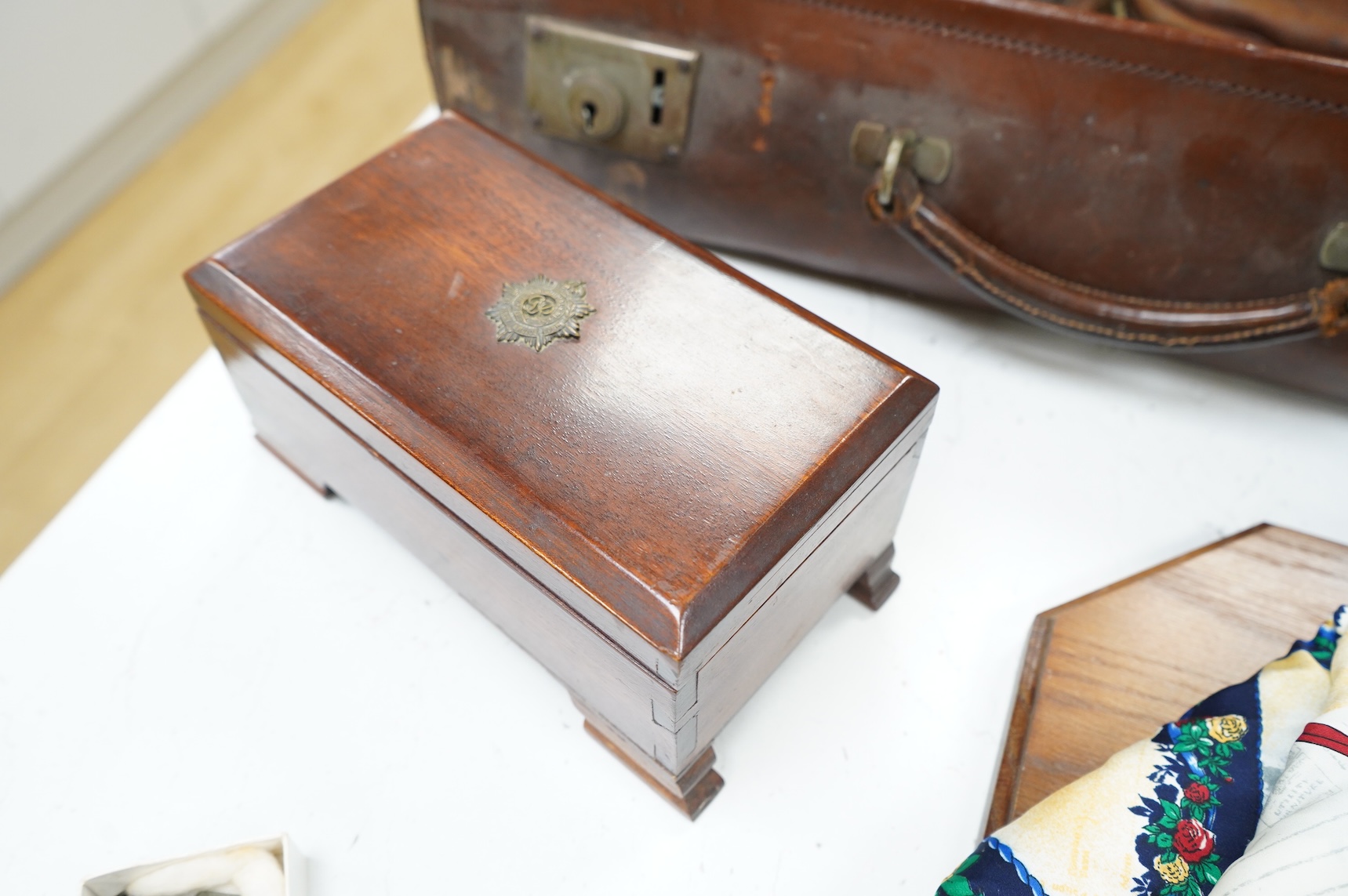 A suitcase of military related items, including; a Manchester Guardian issued early 20th century map of Europe printed on cotton, a First World War trench art match holder the base formed from a cartridge case, two swagg